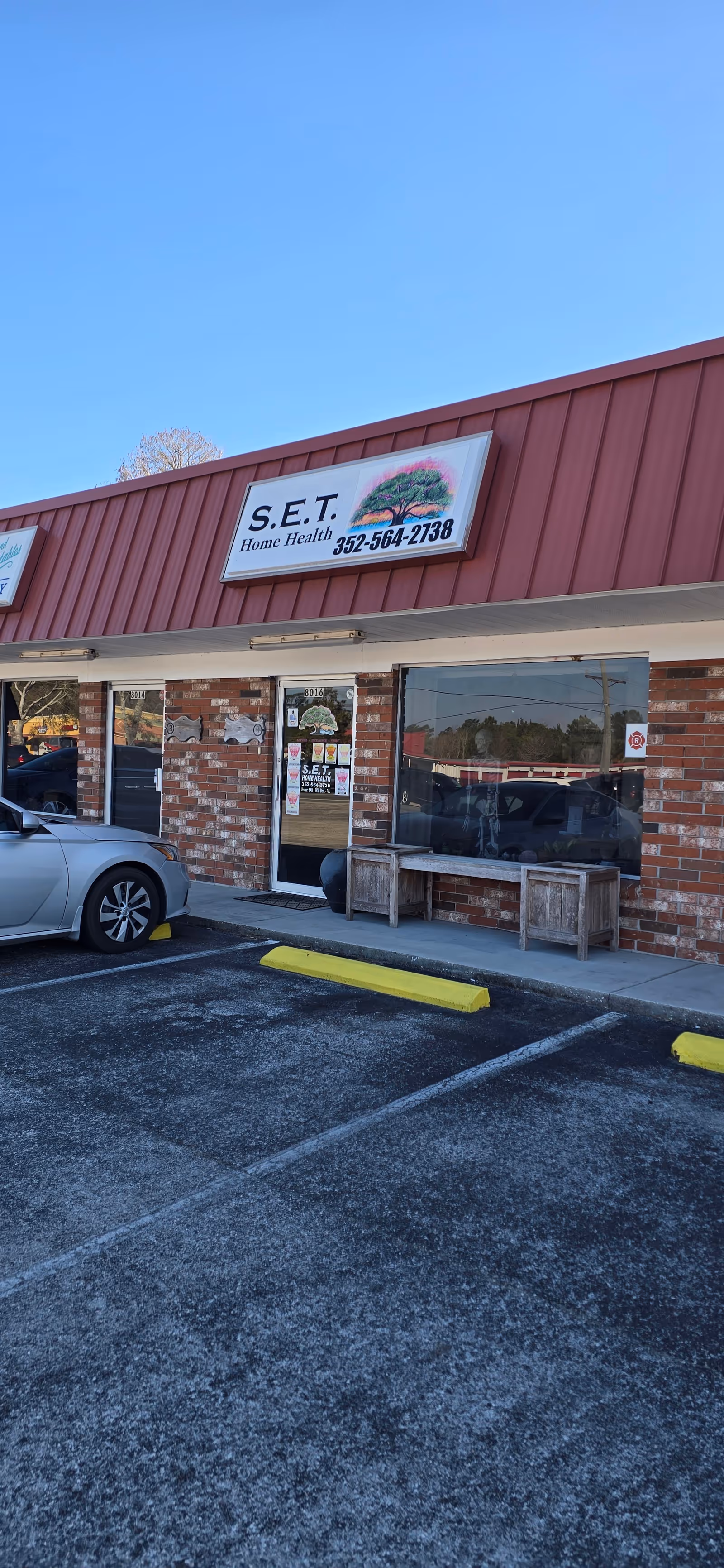 Exterior of a brick storefront with S.E.T. Home Health sign and parking.