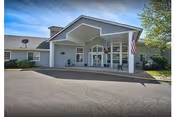 Front entrance of Bridgewood Rivers Assisted Living with porte-cochere, flag, and parking lot.