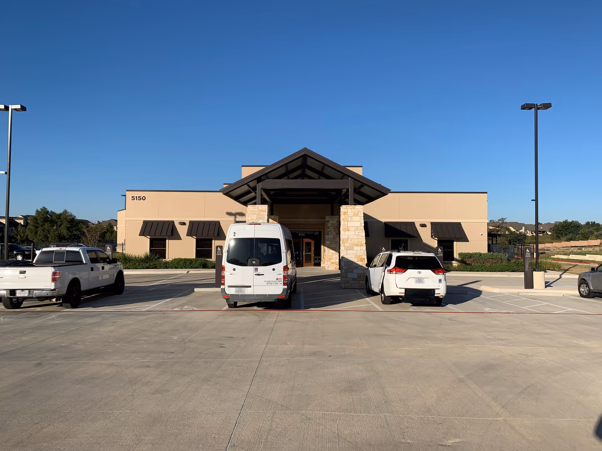 NeuroRestorative facility exterior with a central entry canopy and parked vehicles.