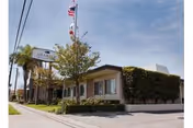Exterior view of Anaheim Healthcare Center with sign, flag, trees, and shrubbery.