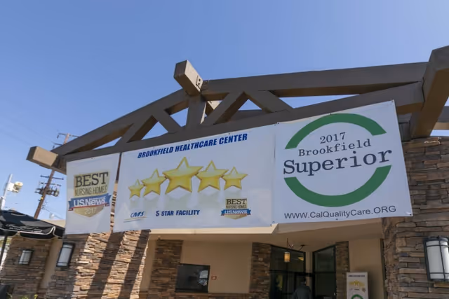 Entrance of Brookfield Healthcare Center with large banners displaying award stars and logos hanging under a wooden pergola.