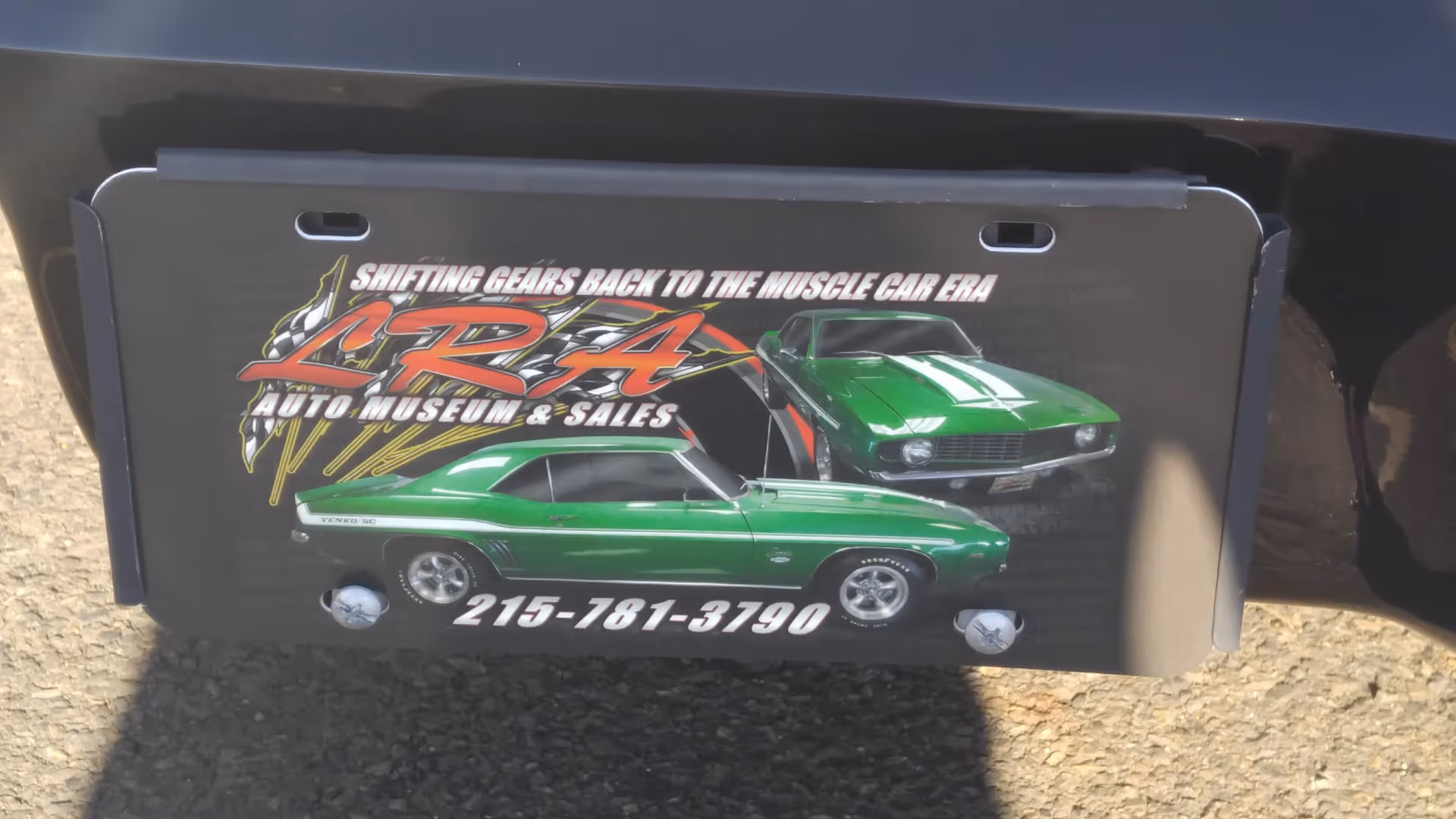Close-up of a vehicle's rear featuring a graphic plate with green cars.