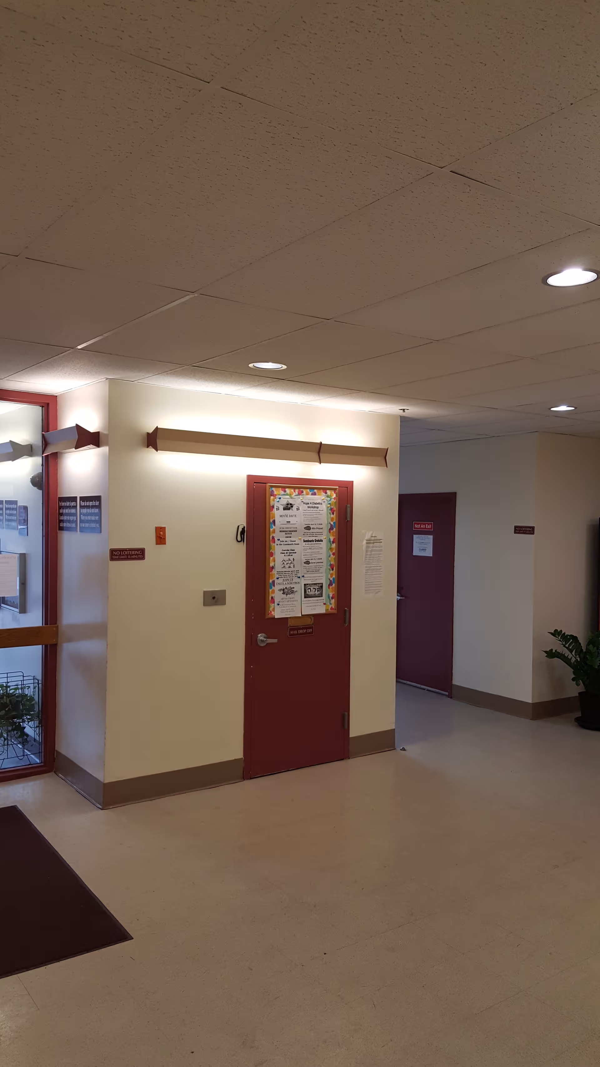 Interior hallway of Barnum House senior living facility with a red door and bulletin board