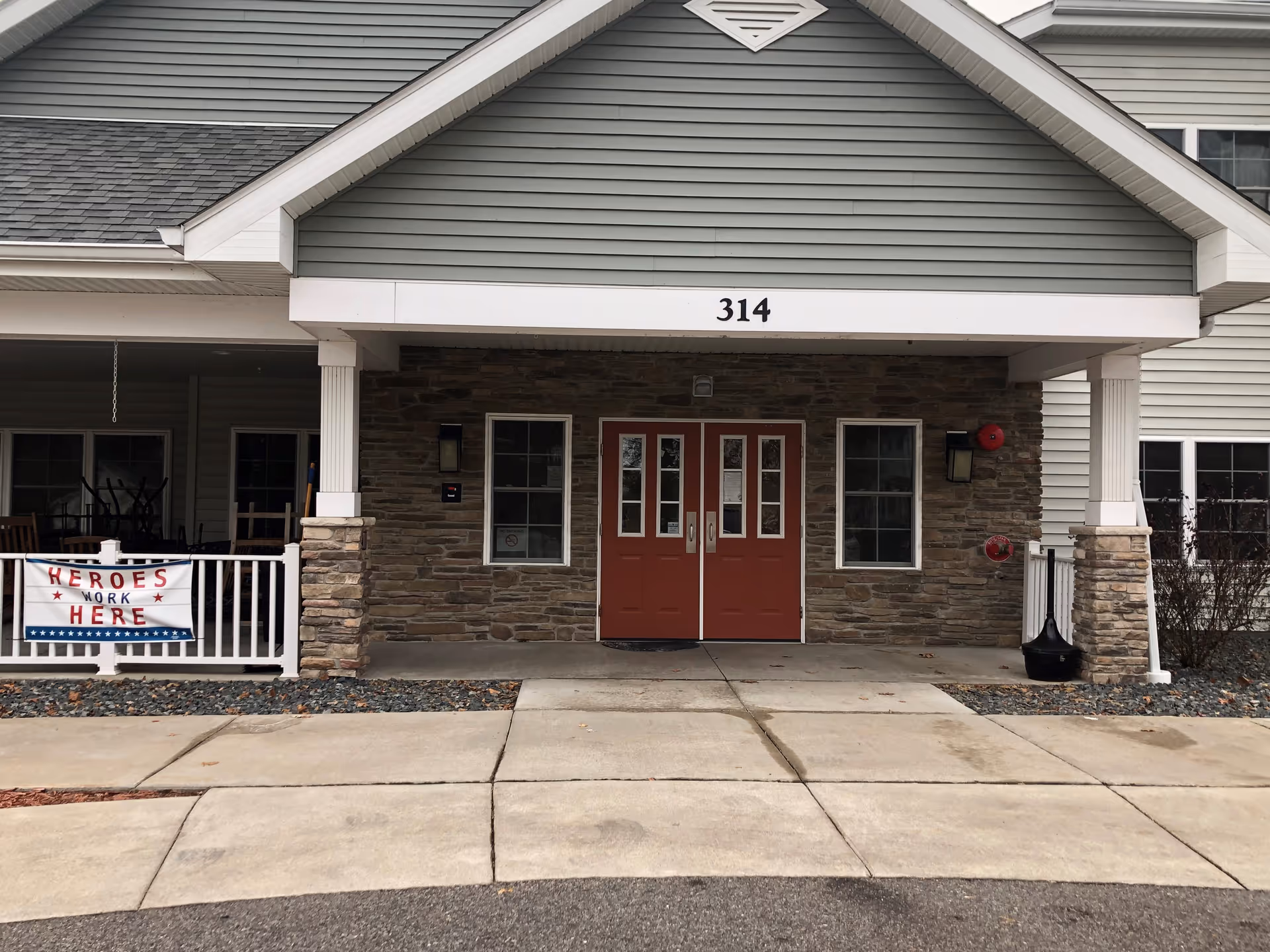Front entrance of Milestone Senior Living Tomahawk with red doors and stone facade.
