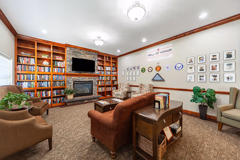 A cozy Birds of Paradise Home lounge with a fireplace, bookshelves, and seating.