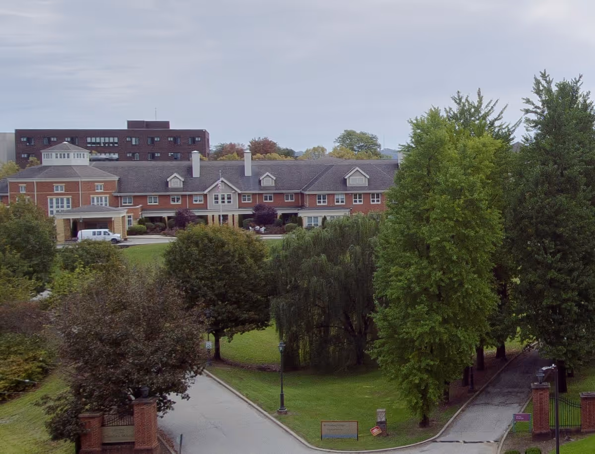 Front view of a brick senior living campus with trees and a circular driveway.
