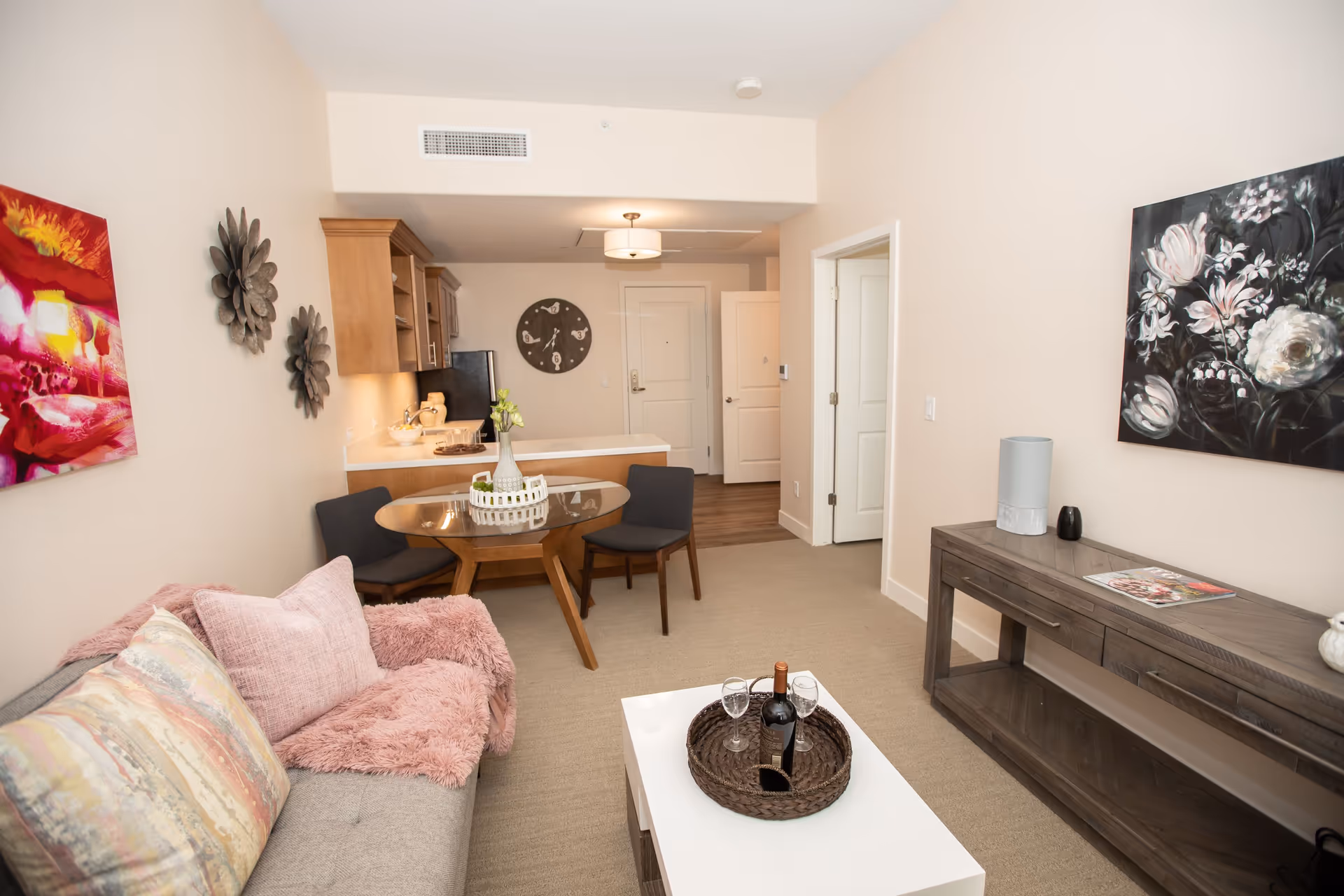 Cozy living room with sofa, coffee table, round dining table, and kitchen in background.