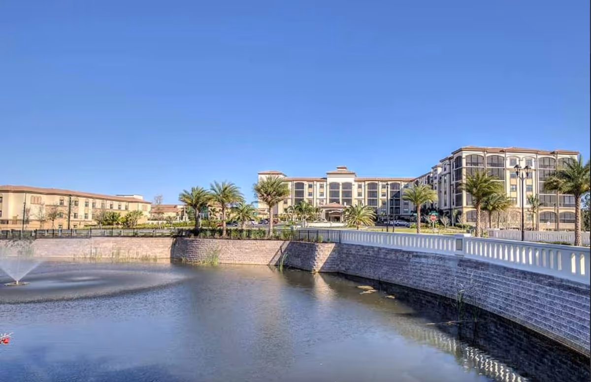 A Stillwater Health Care campus exterior featuring a water feature, palm trees, and a multi-story building.