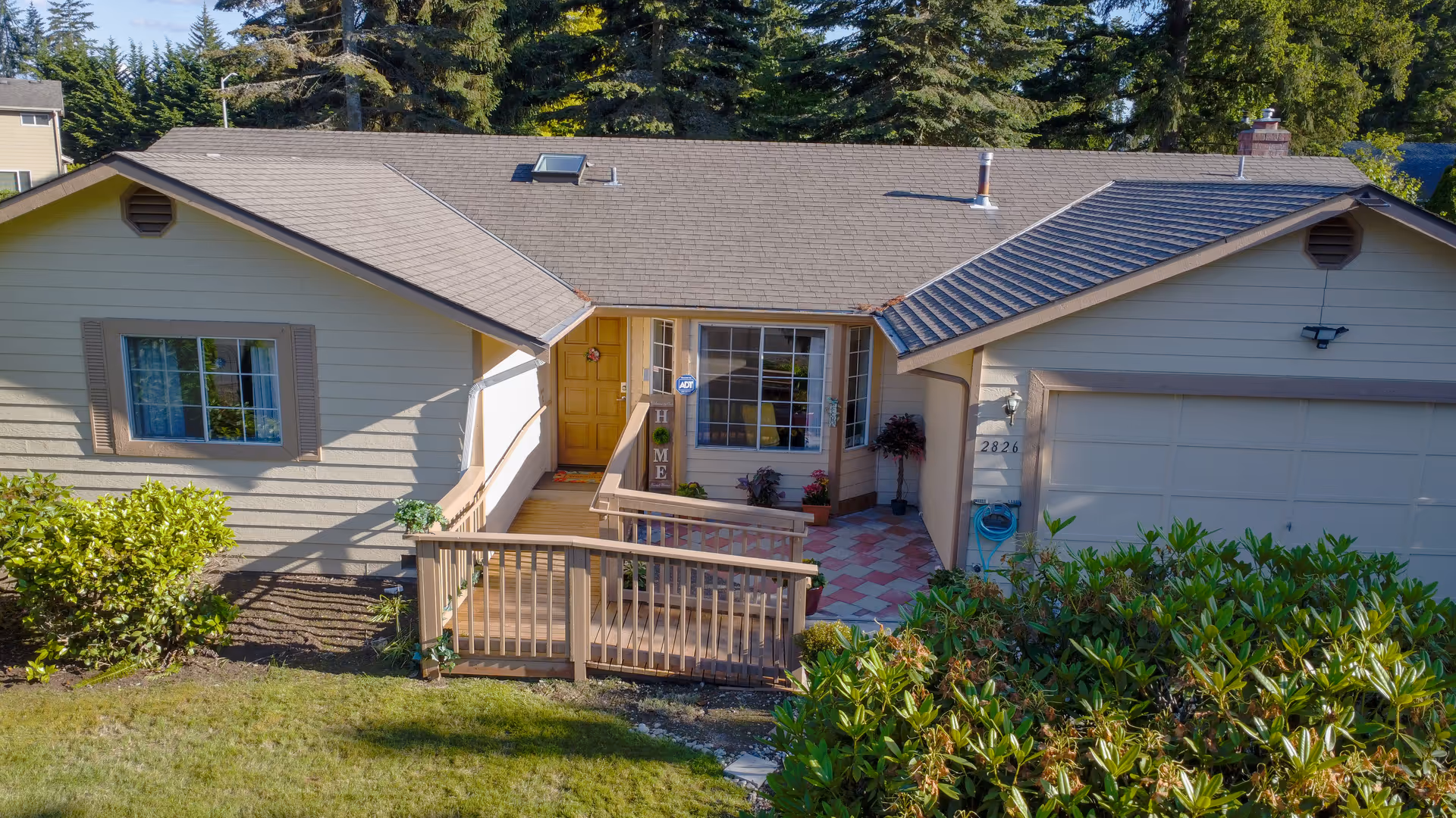 Front view of a single-story home with a small wooden porch, steps, and green shrubbery.