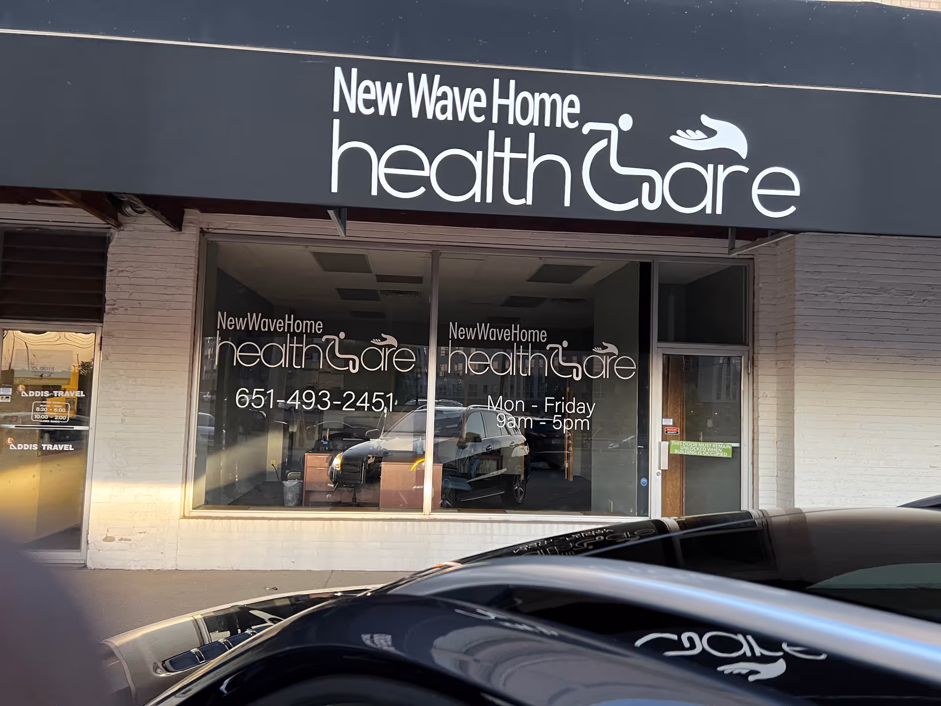 Exterior storefront for New Wave Home Health Care with large sign and glass windows.