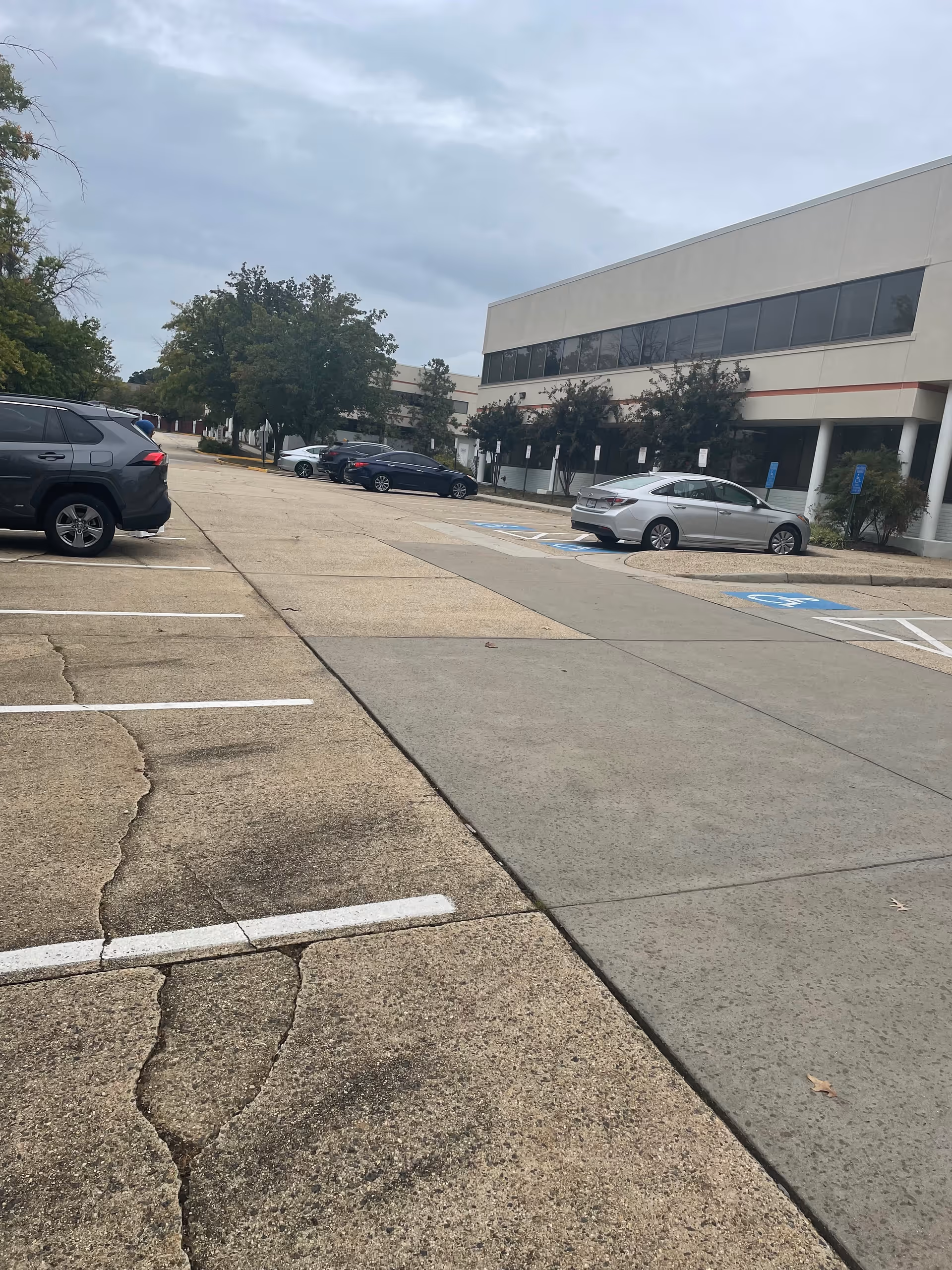 Exterior view of a senior care facility with a parking lot and several parked cars.