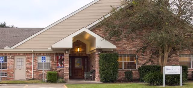 Brick senior care facility entrance with a covered porch and landscaped front.
