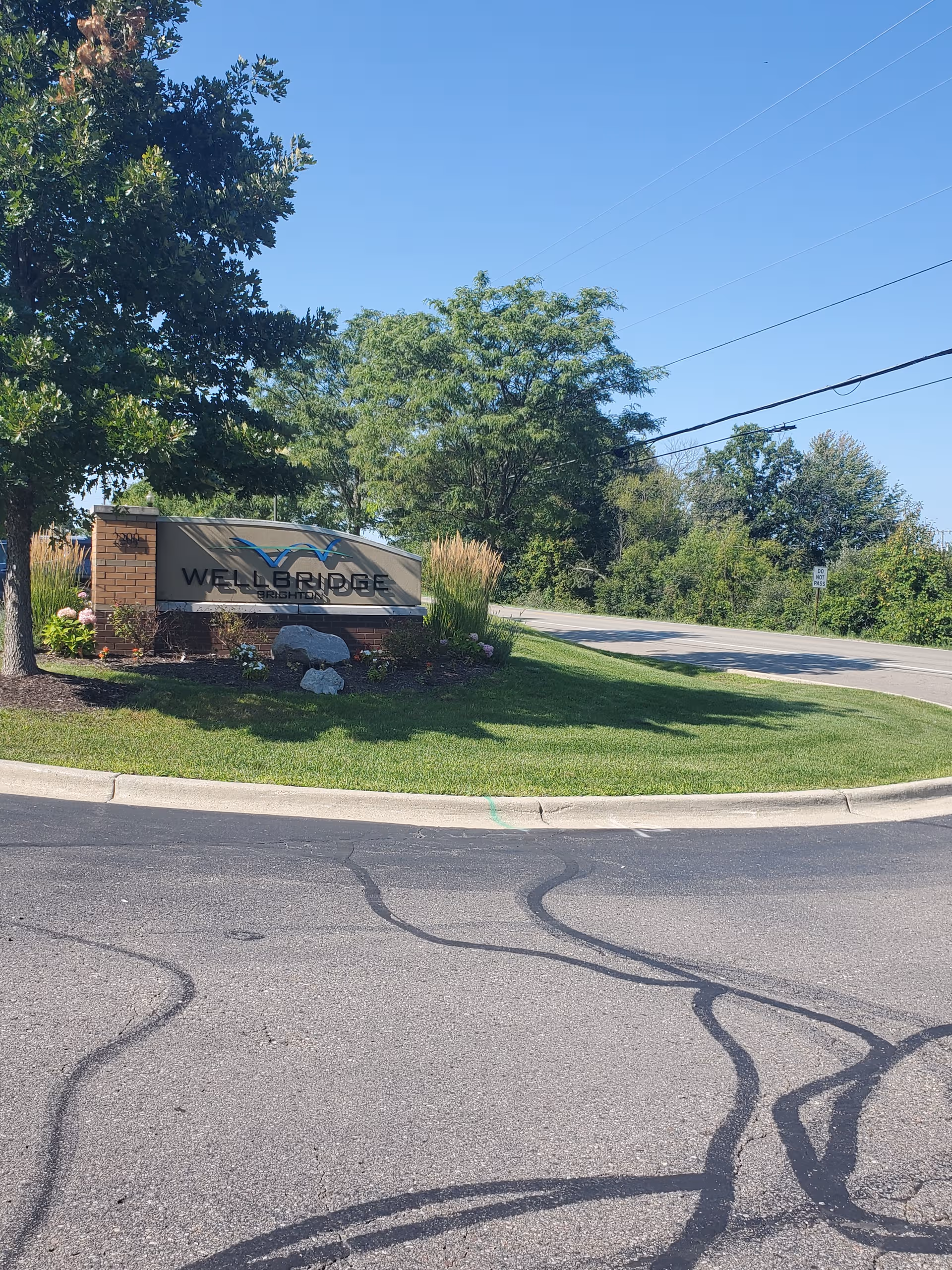 Exterior view of WellBridge of Brighton sign with landscaping beside a road
