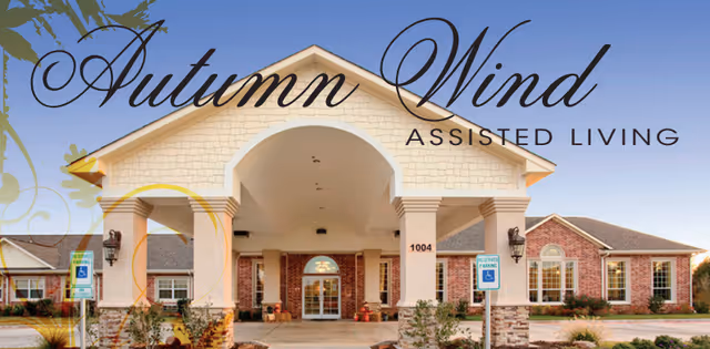 Front entrance of Autumn Wind Assisted Living with arched canopy and brick exterior.