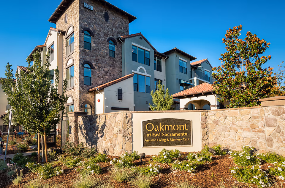 Exterior view of Oakmont of East Sacramento with stone wall and landscaped entrance.