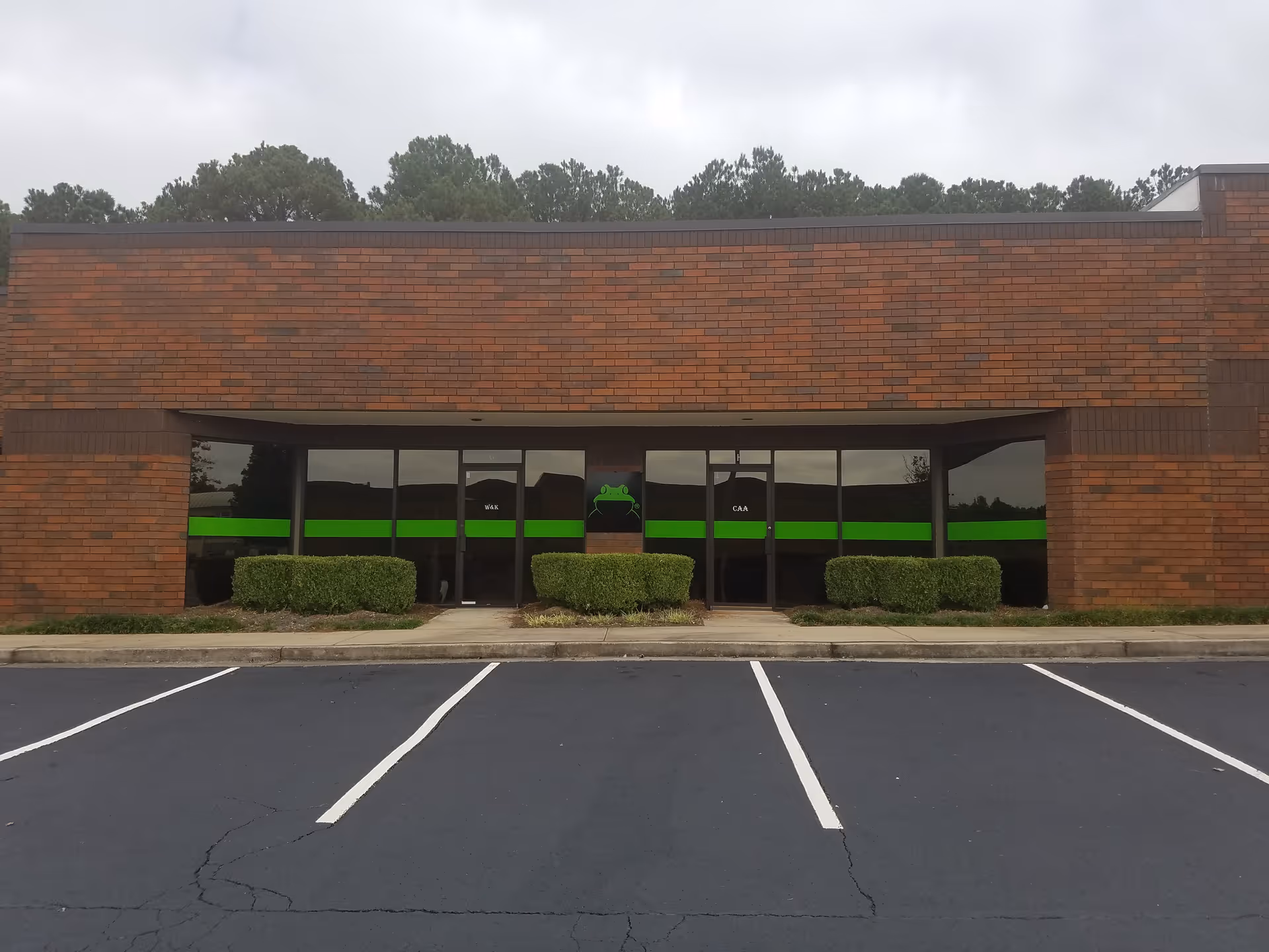 Brick building exterior with glass doors and a green stripe across.