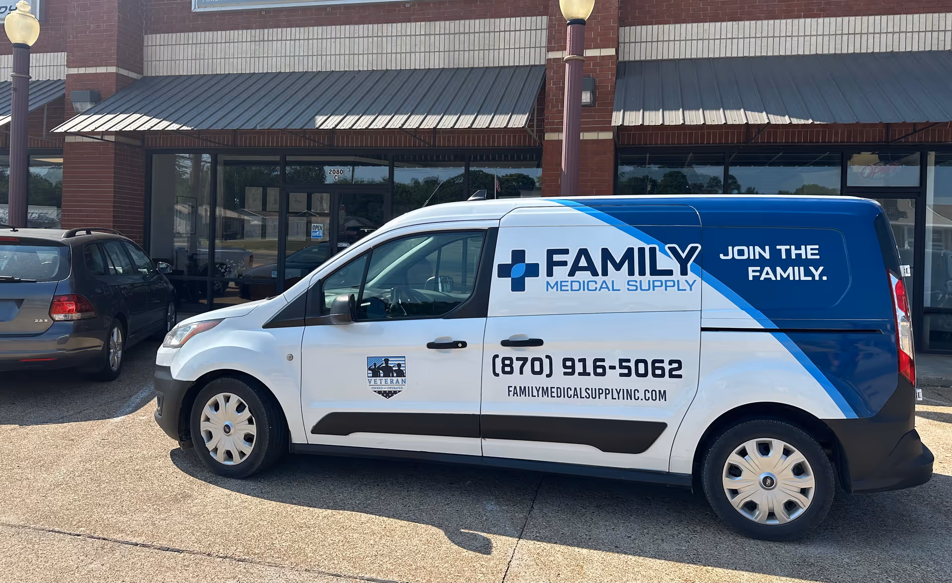 White and blue Family Medical Supply van parked in front of a storefront.