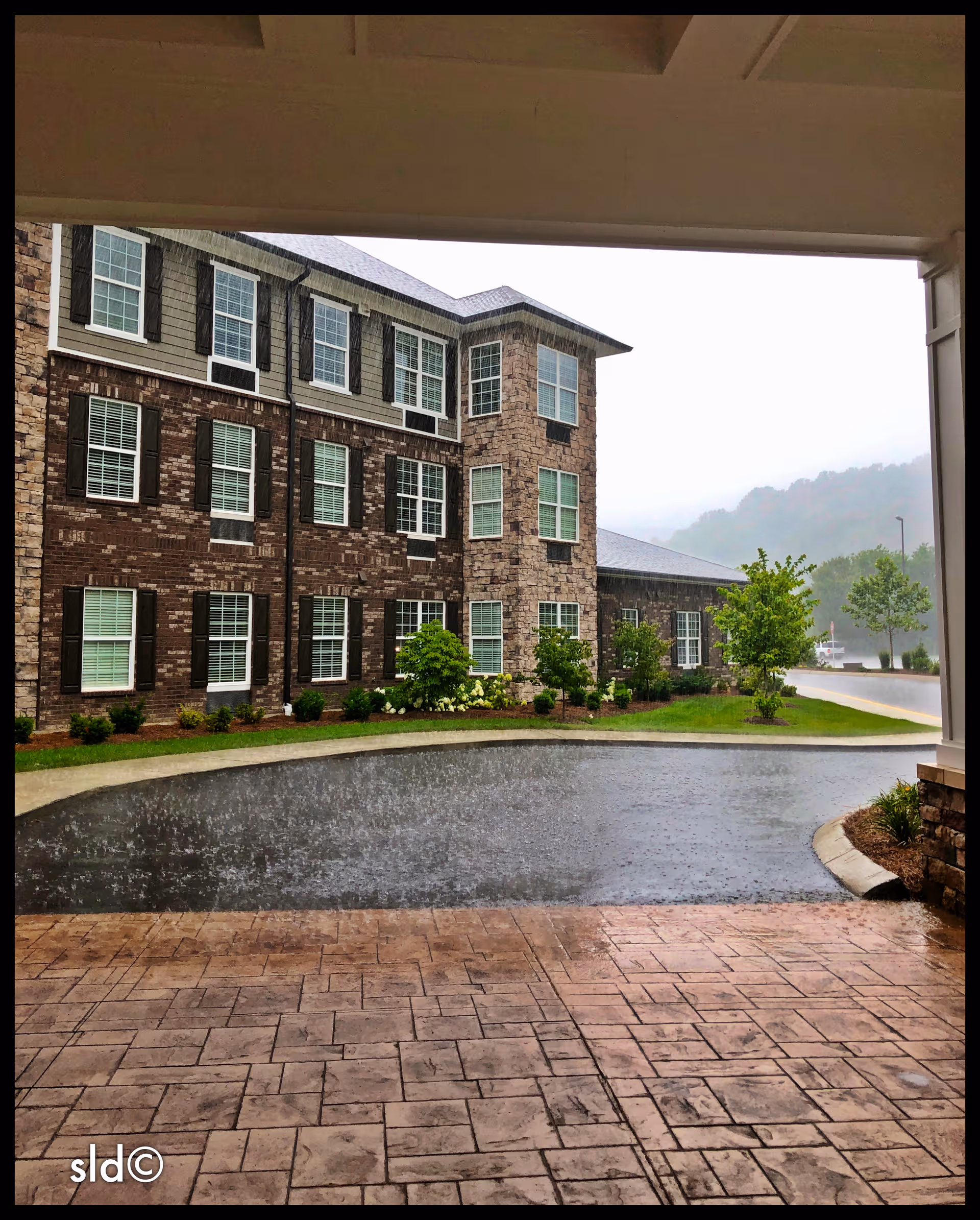 Exterior view of Canterfield Senior Living building with brick facade, windows, and a rainy driveway.