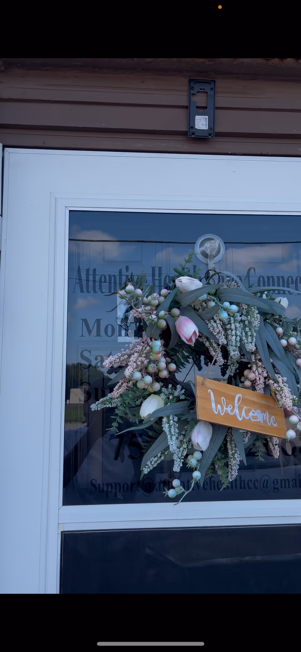 Entrance door with a floral wreath and welcome sign.