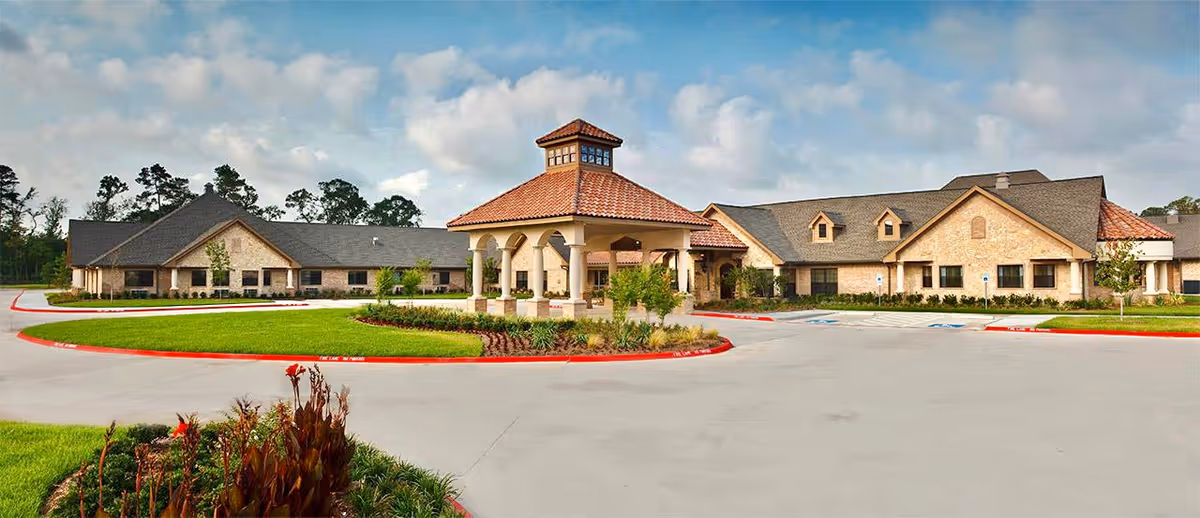 A large single-story senior living facility with brick walls, a central covered entrance, and landscaped grounds.