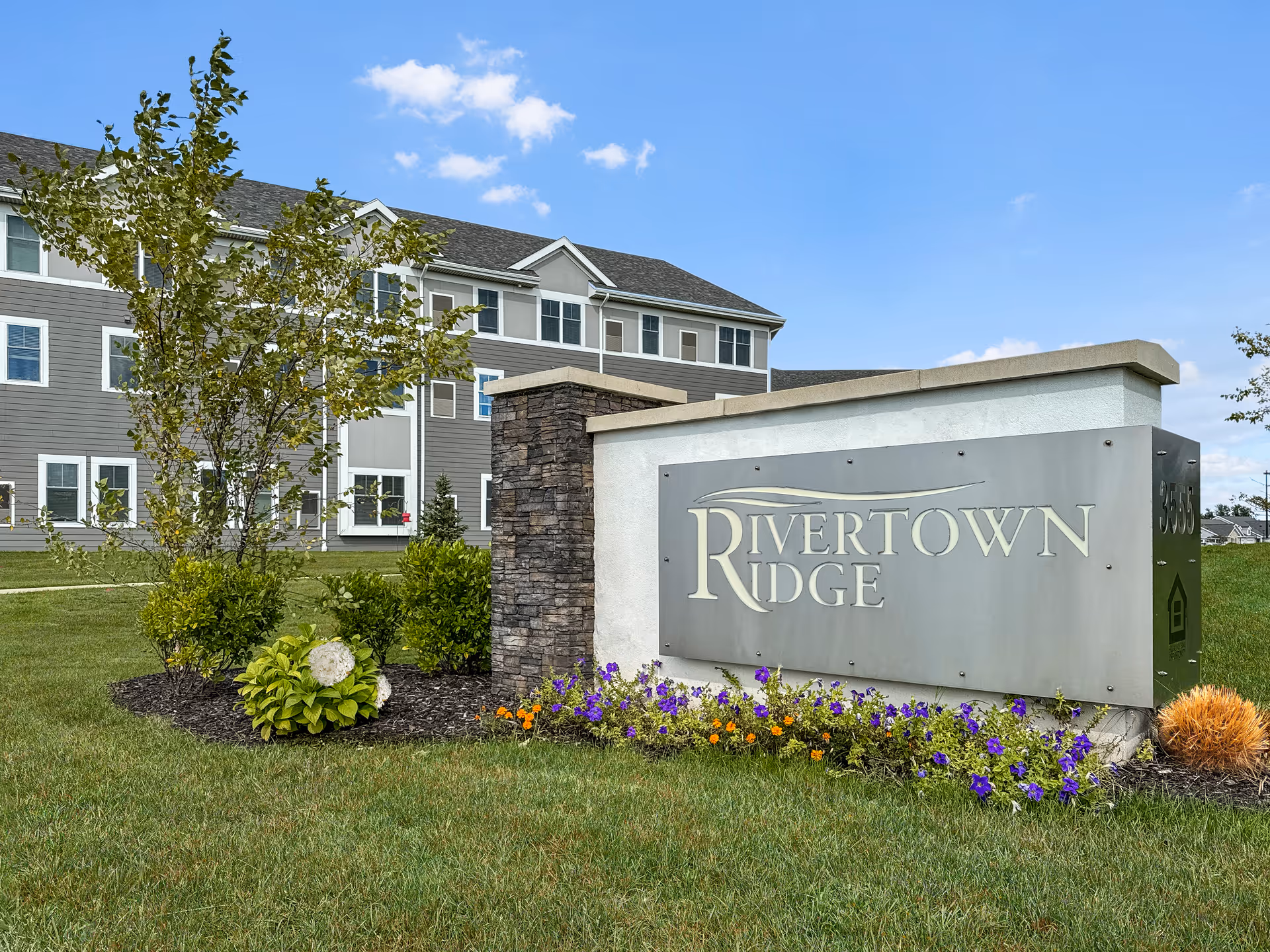 Exterior view of Rivertown Ridge facility with a landscaped sign and a multi-story building.