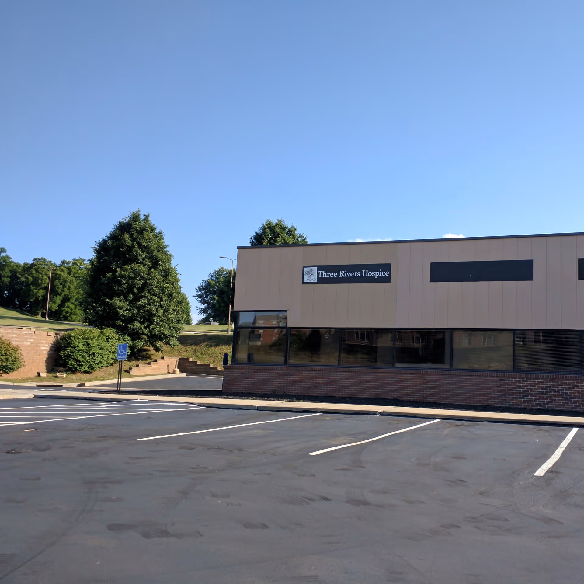 A single-story hospice building with a Three Rivers Hospice sign and a parking lot.