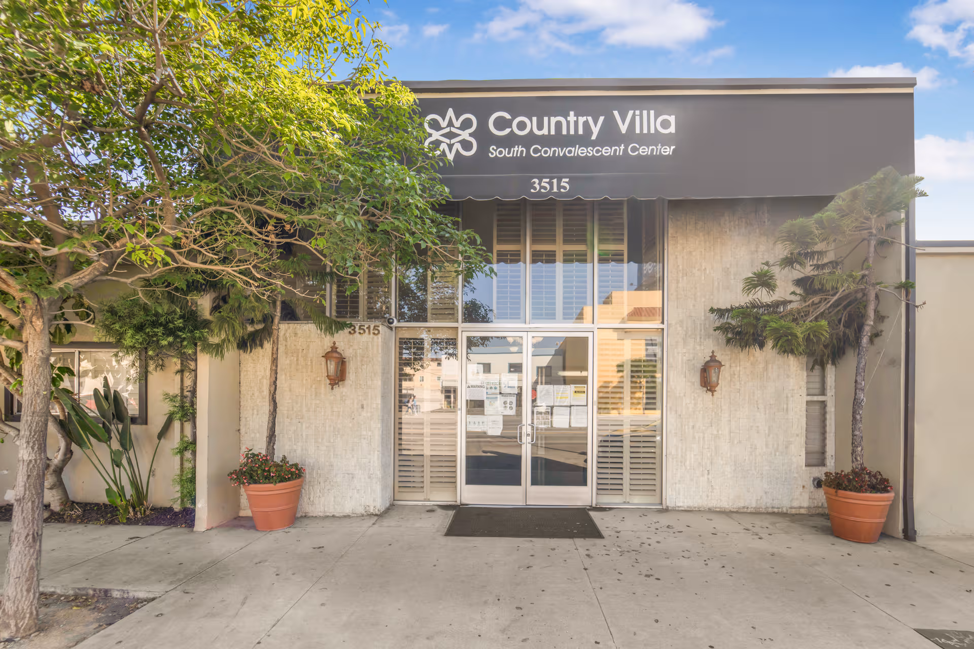 Elegant facility entrance with double doors, trees, and potted plants in front of a senior center.