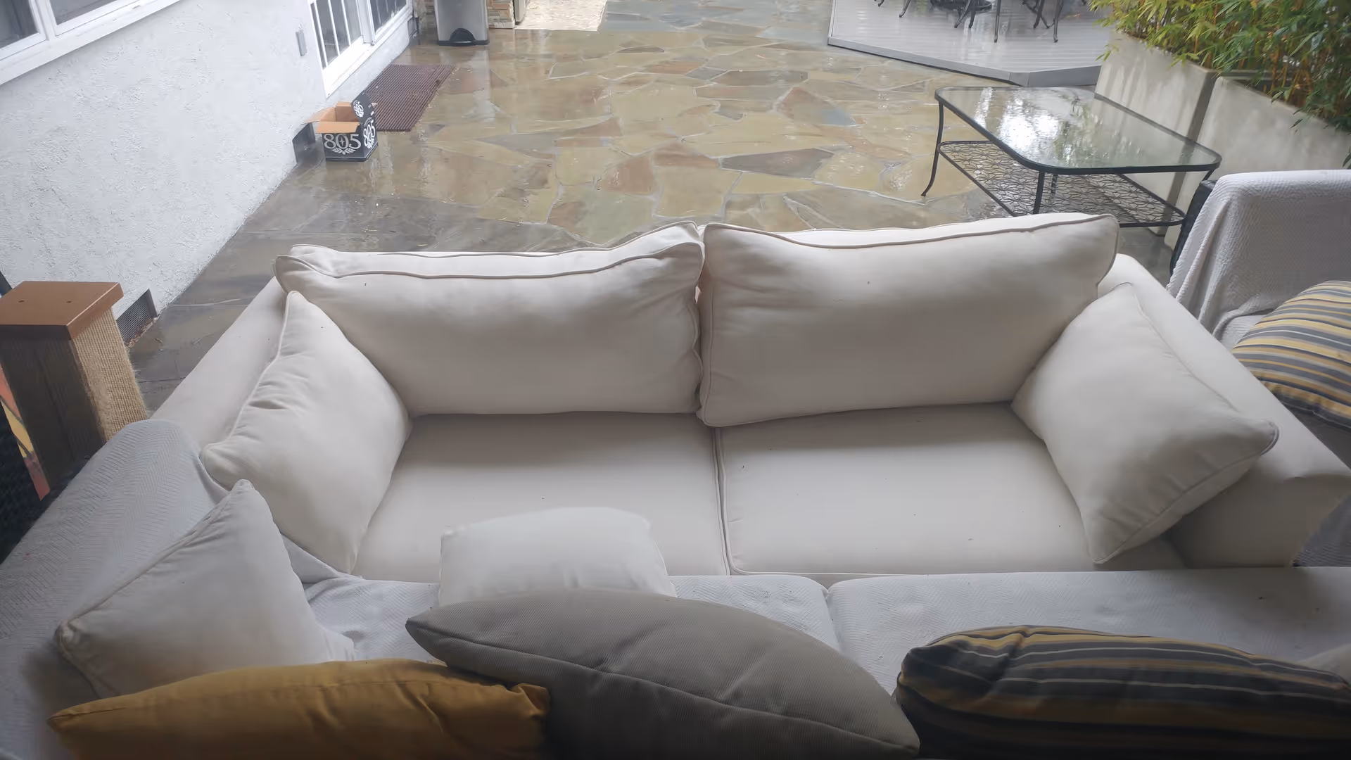 Outdoor patio with beige sectional sofa and glass table at My Mother's Place.
