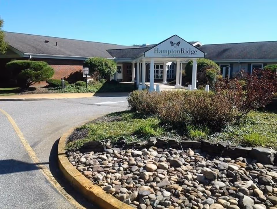 Entrance and front canopy of Hampton Ridge Healthcare & Rehabilitation with landscaped rock bed and driveway.