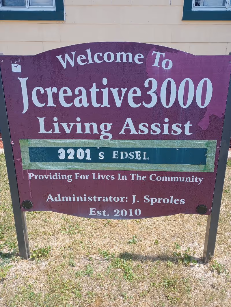 Purple exterior sign for Jcreative3000 Living Assist outside a building.
