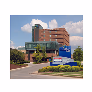 Exterior view of Jennie Stuart Health building with blue sky, trees, and a sign.