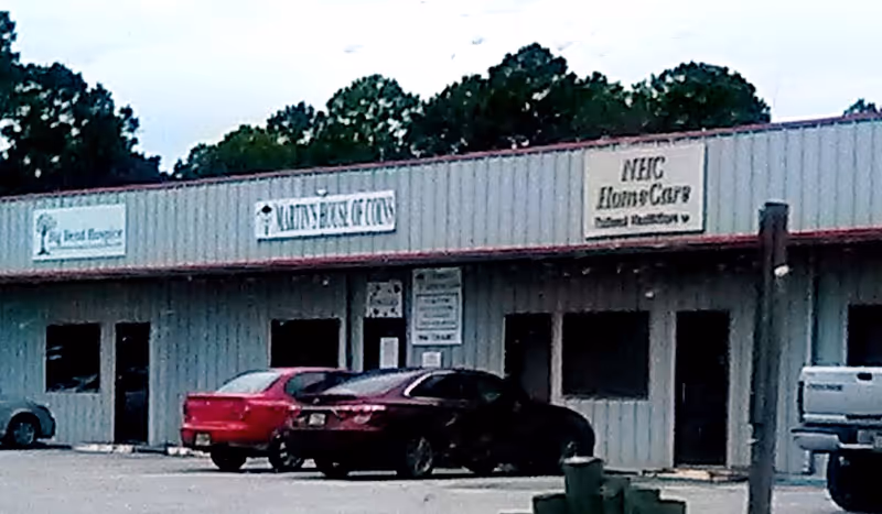 Exterior view of a metal storefront building with NHC HomeCare sign and parked cars.