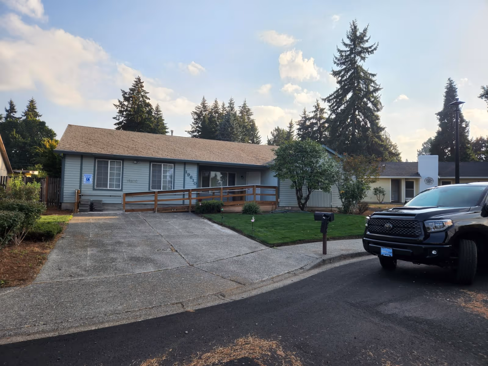 Exterior of Blissful Foster Home: single-story facility with ramp, driveway, lawn, and a black pickup.