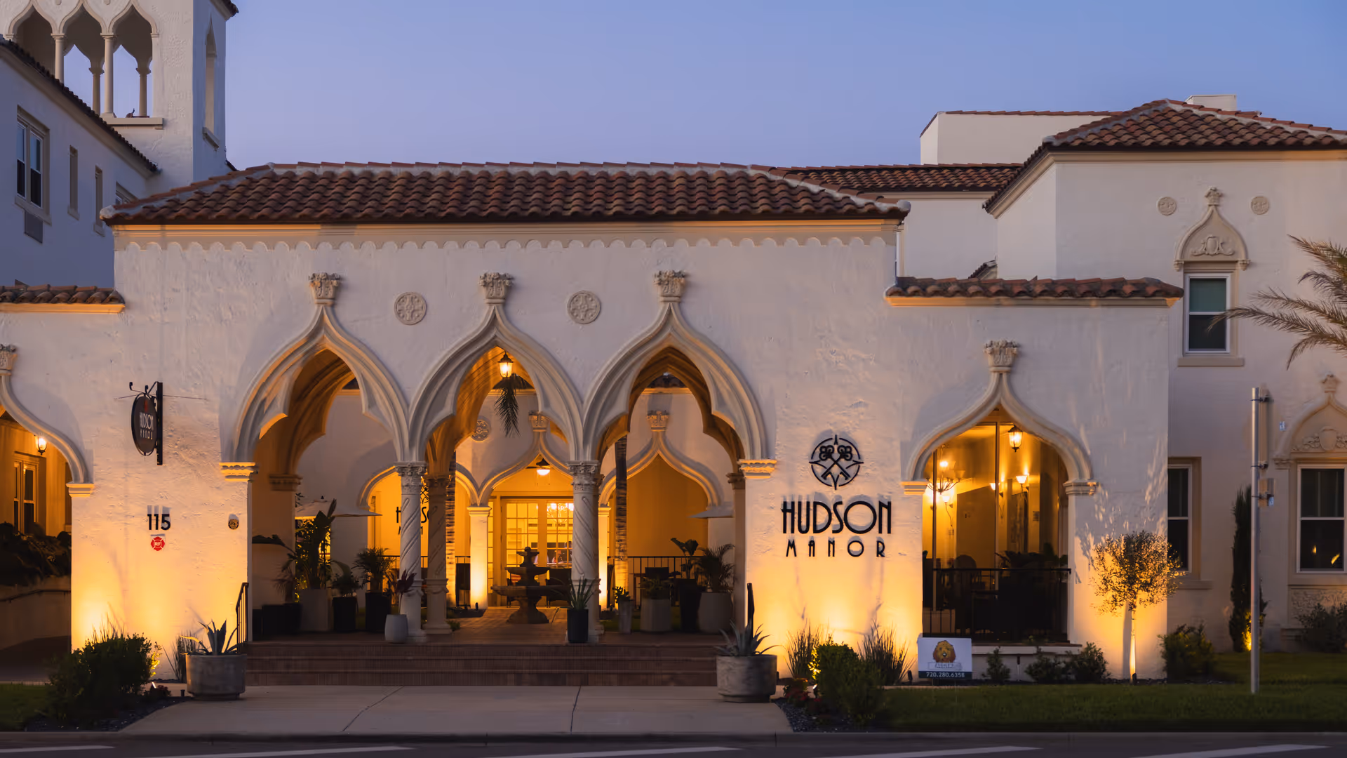 Dusk view of the Hudson Manor building front showing illuminated arched entrance and signage.