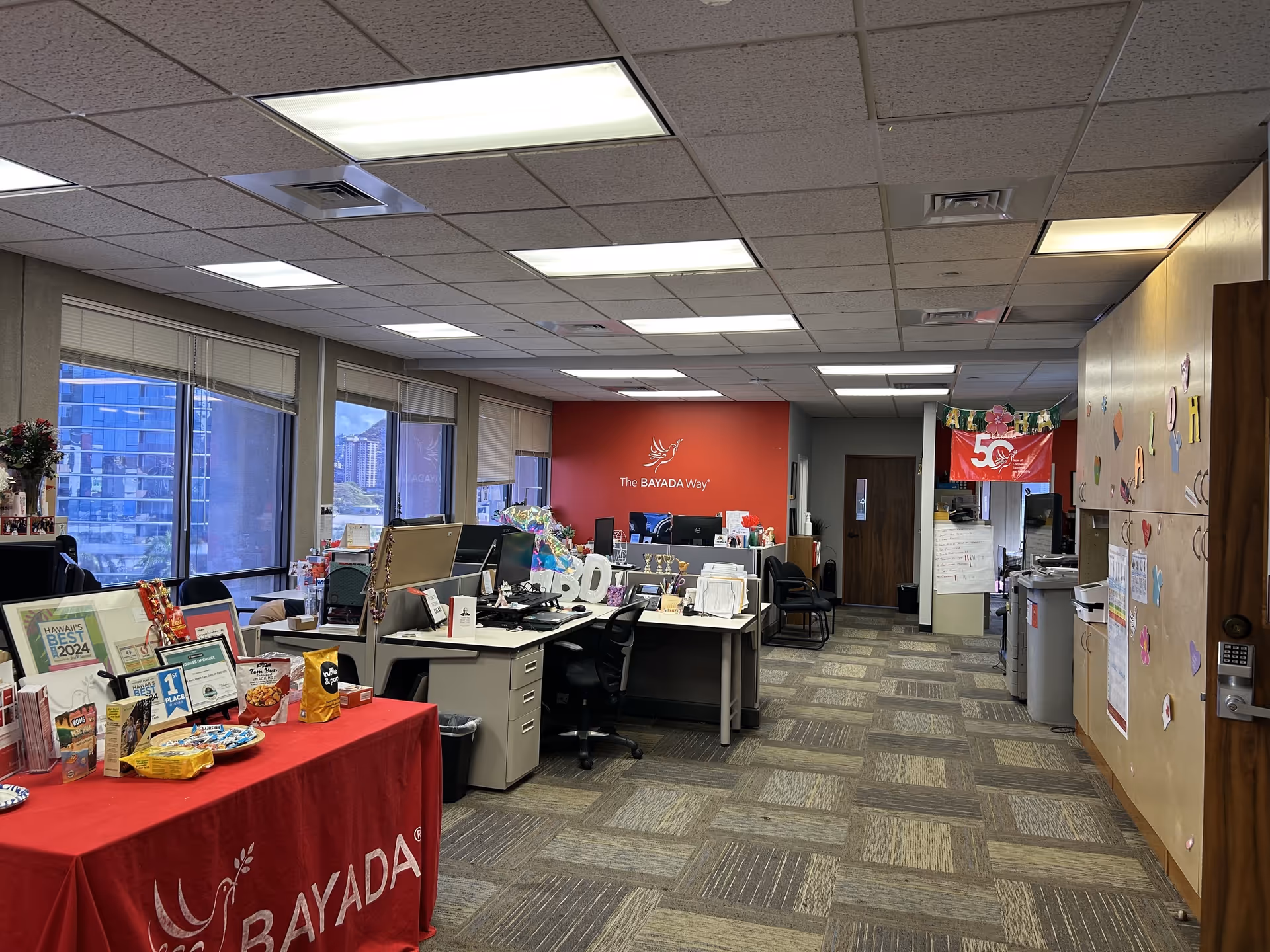 Open office area with desks and computers under a red BAYADA wall.