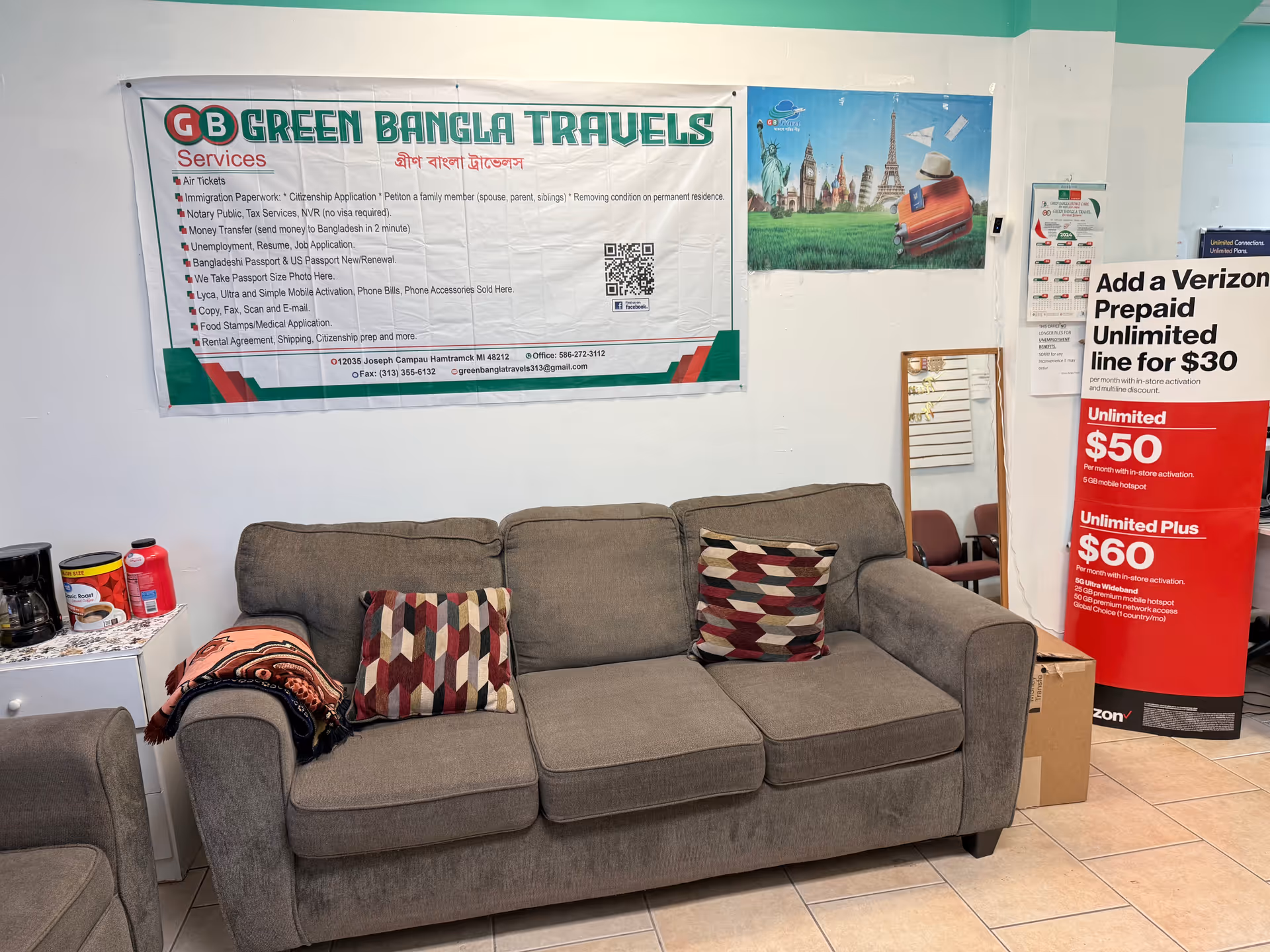A gray couch with cushions sits in a bright lobby area with posters.