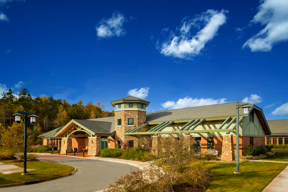 Exterior view of VIA Health Partners senior living facility with stone entrance under a blue sky.