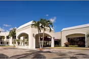 Front exterior of Encore at Boca Raton Rehabilitation and Nursing Center with arches and palm trees.