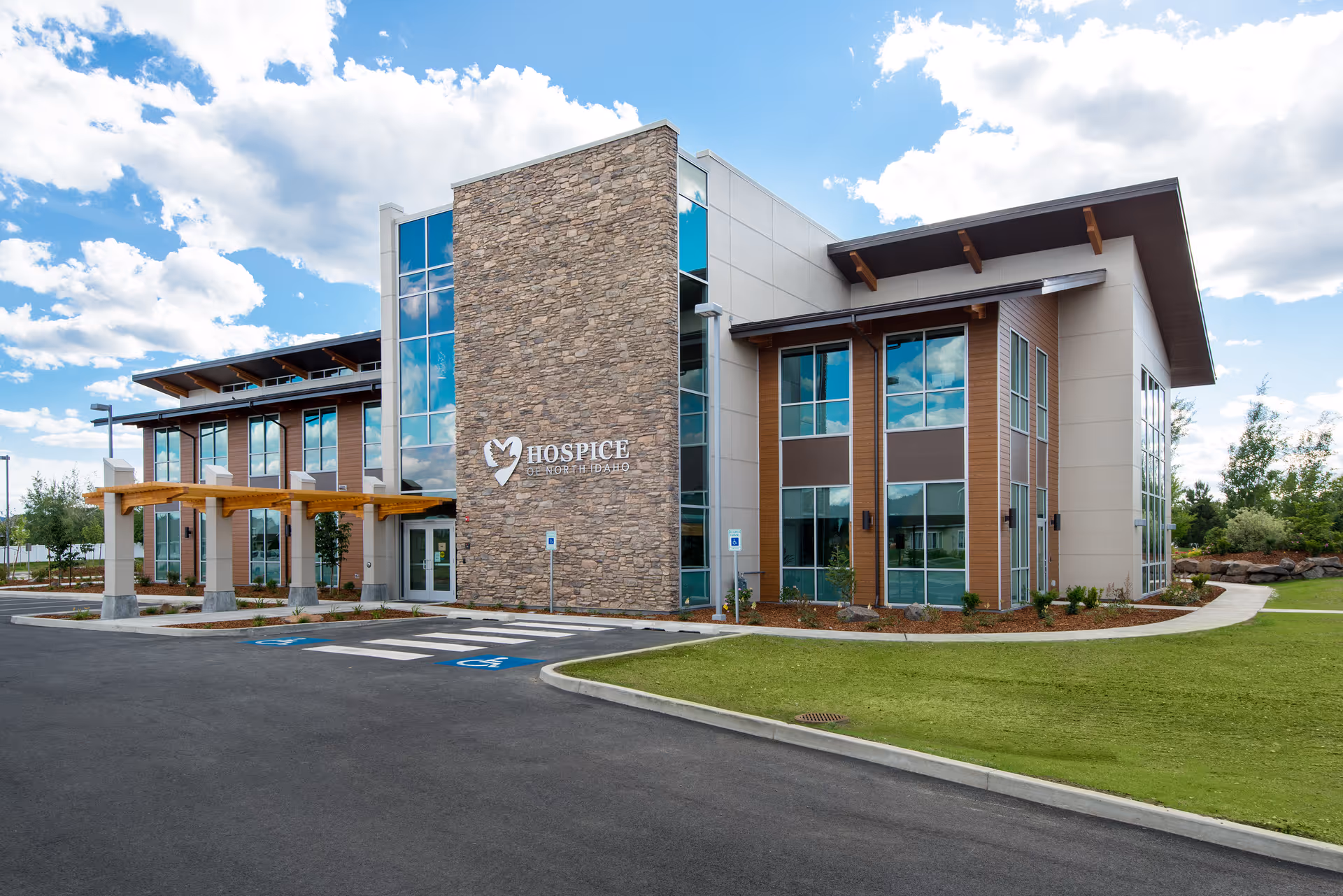 Exterior view of a modern hospice building with stone facade and glass windows.