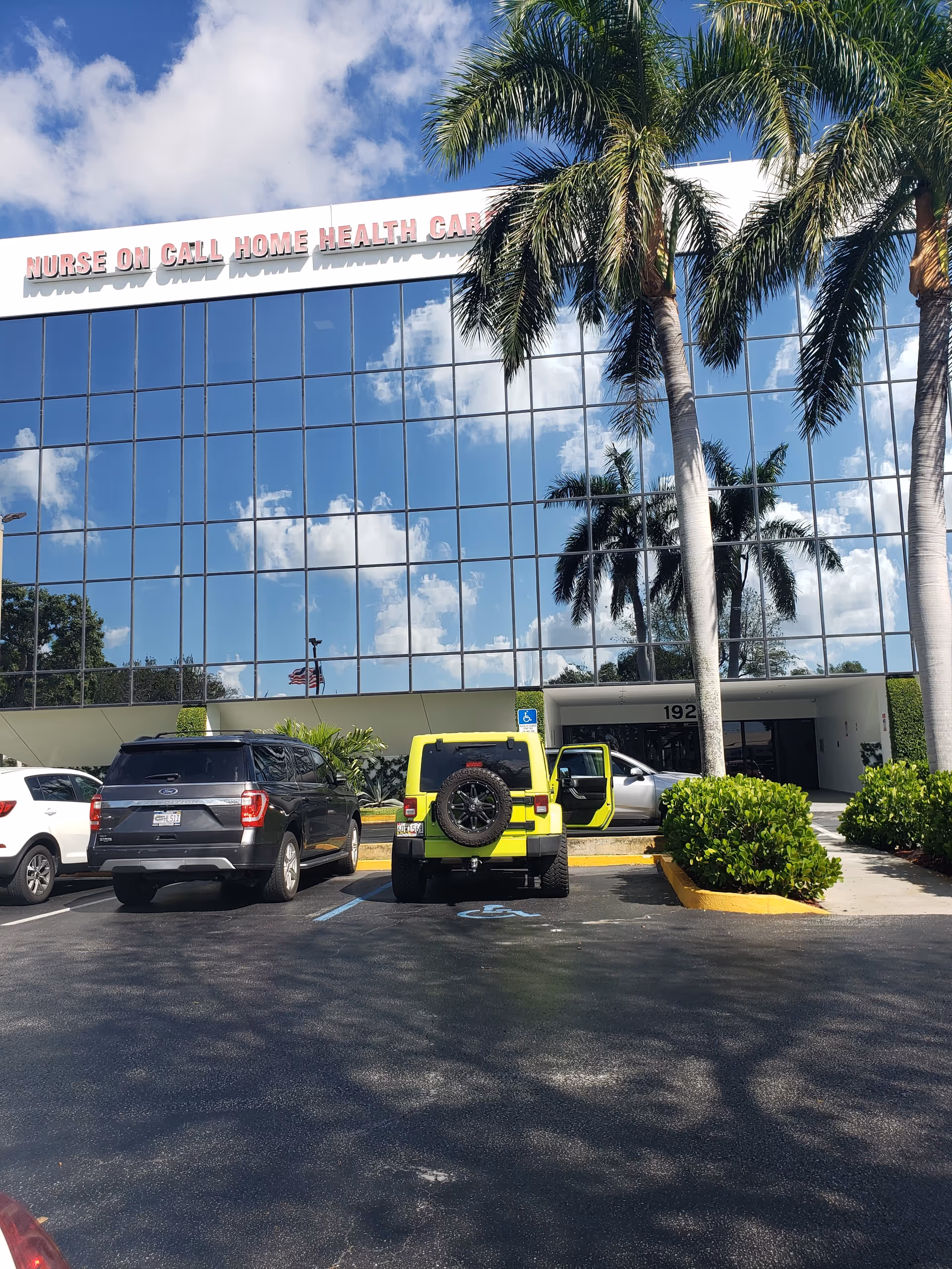 Glass-fronted building labeled Nurse On Call Home Health Care with parked cars and palm trees.