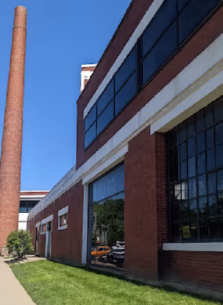 Exterior view of a brick senior living facility with large windows and a sidewalk.