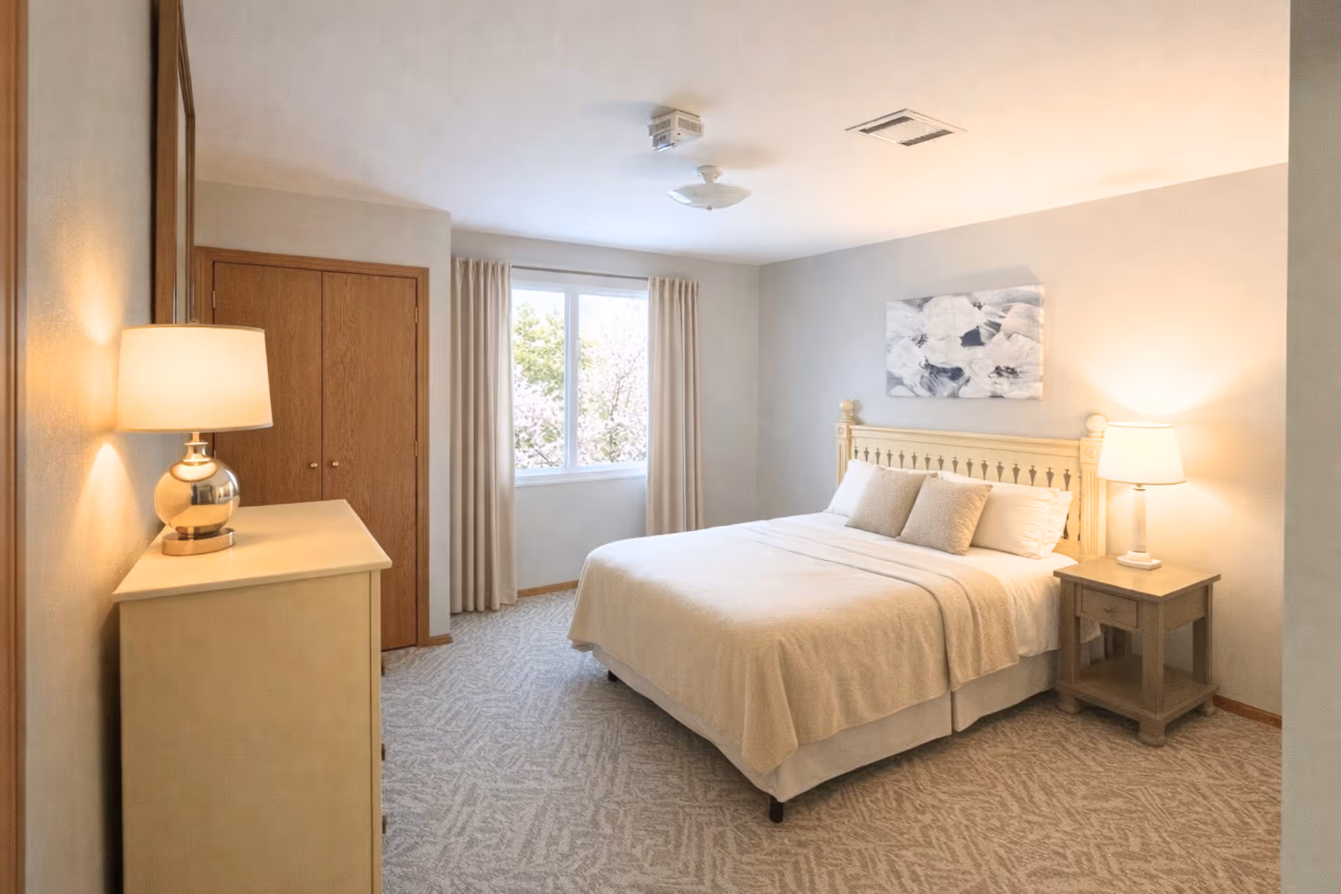 A Cardinal Grove senior living bedroom with a bed, dresser, nightstands, and a large window.