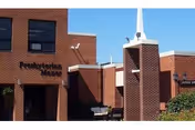 Exterior brick building with entrance sign reading Presbyterian Manors III and a white spire.