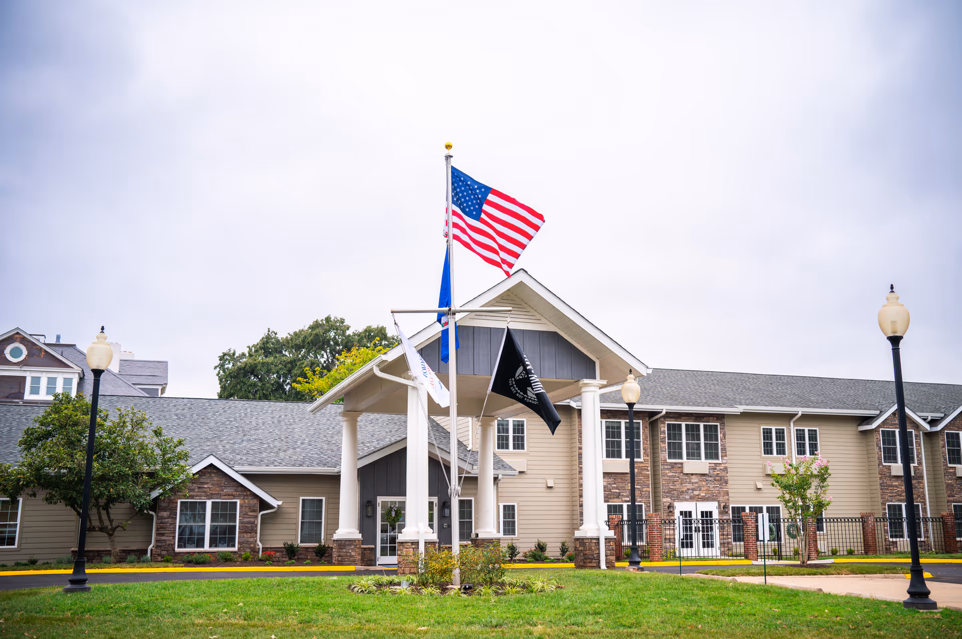 Exterior front view of Commonwealth Senior Living at Manassas with flags and pillars.