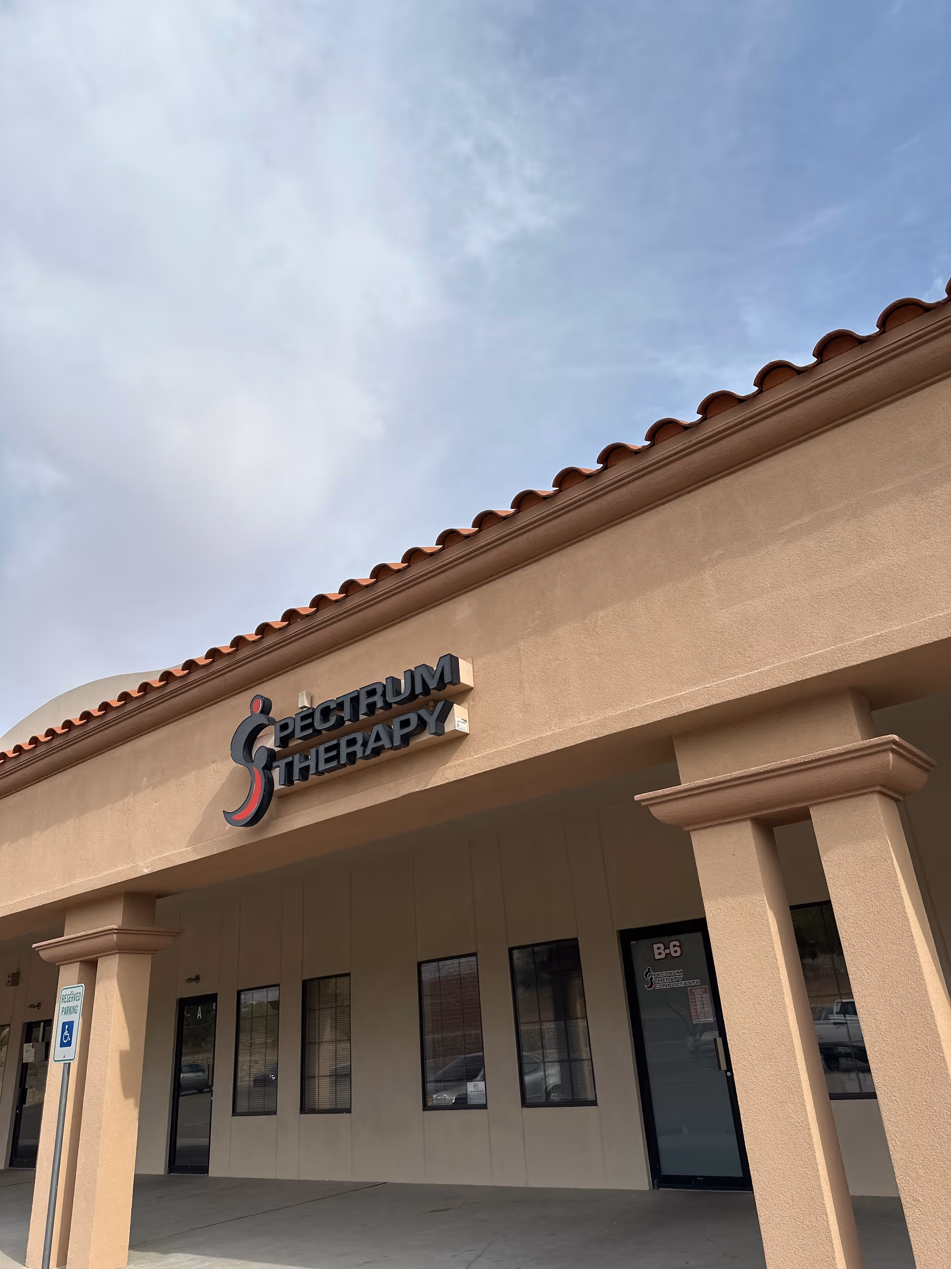 Exterior view of Spectrum Therapy Consultants building with beige stucco and a tiled roof.