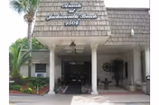 Entrance of Avante Villa at Jacksonville Beach facility showing a covered driveway with two columns, a hanging lantern, plants on either side, and the facility name and address displayed above the entrance.