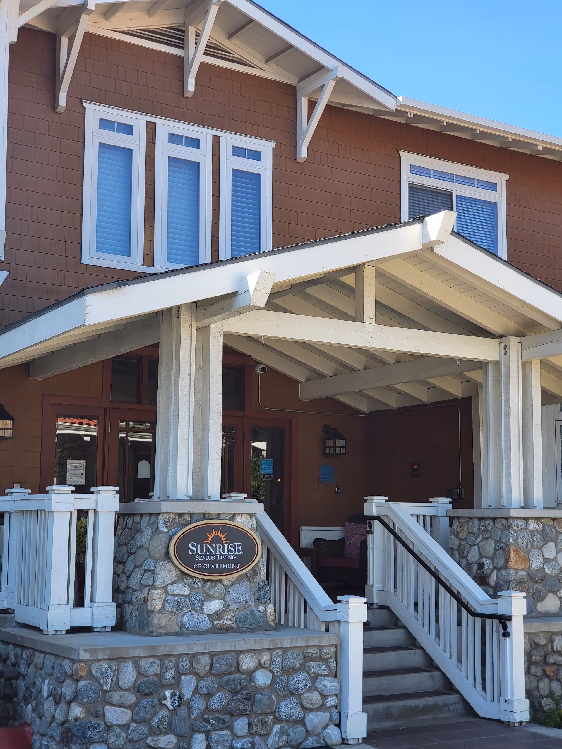 Front entrance of Sunrise Senior Living of Claremont, with stone porch and stairs.