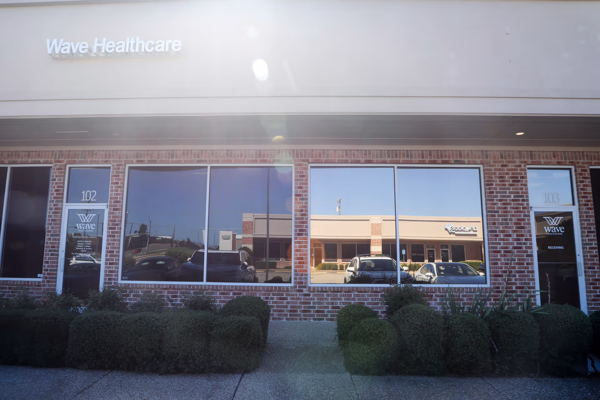Wave Healthcare Temple storefront exterior with brick facade, large windows, and landscaped shrubs.