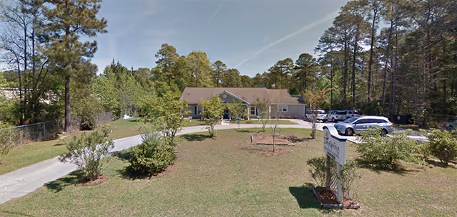 Exterior view of Dayspring Assisted Living with a curved driveway, parked cars, and a front sign.