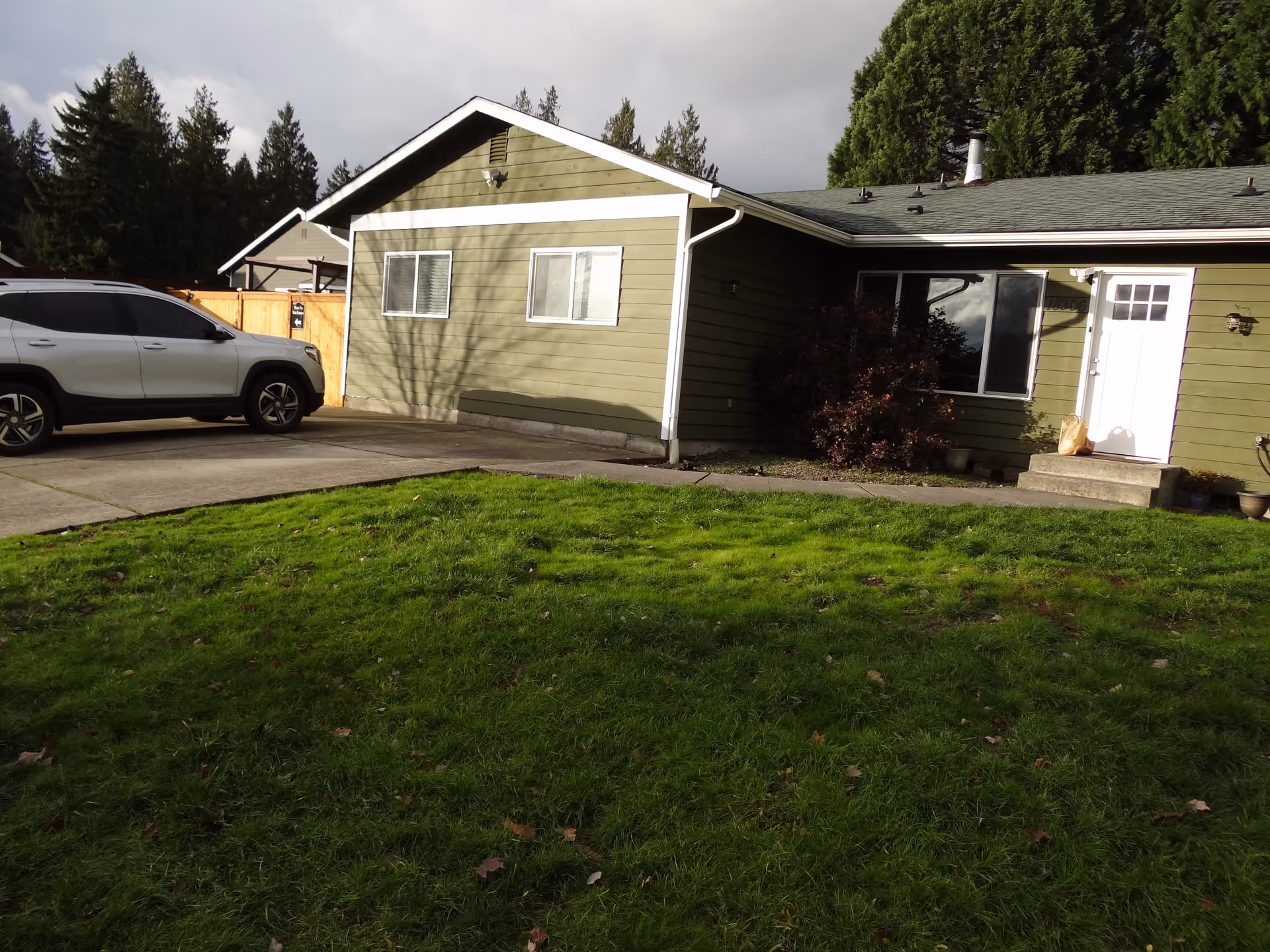 Green single-story residence with driveway, white SUV, and a well-kept front lawn.